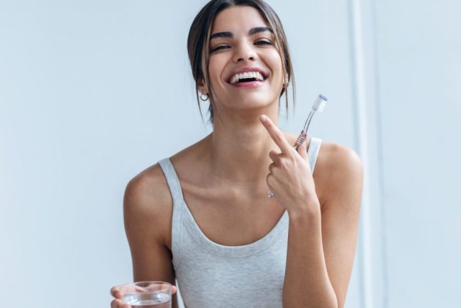 Shot,Of,Pretty,Young,Woman,Brushing,Her,Teeth,While,Looking cosmetic dentist near auburn